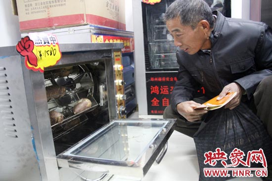 一名科技會員在看一臺自動化烤紅薯機器 一名科技會員在看一臺自動化烤紅薯機器