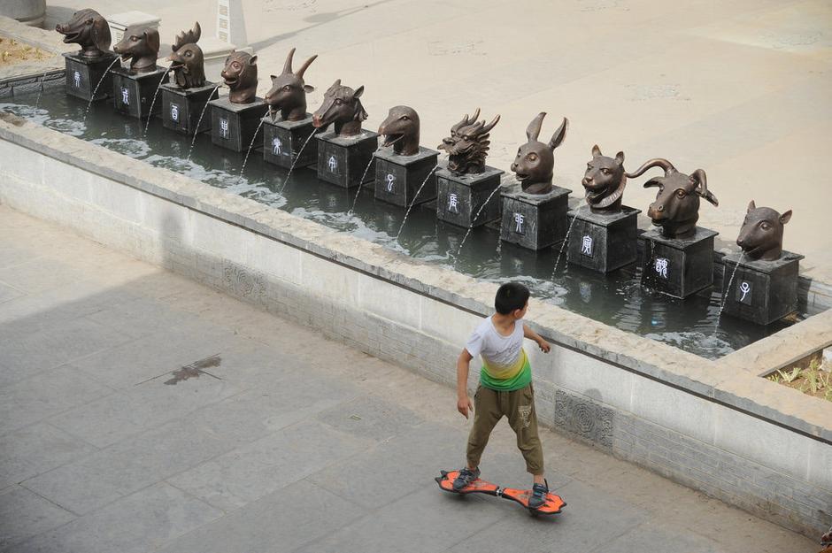 圖為一名市民從獸首旁經(jīng)過。