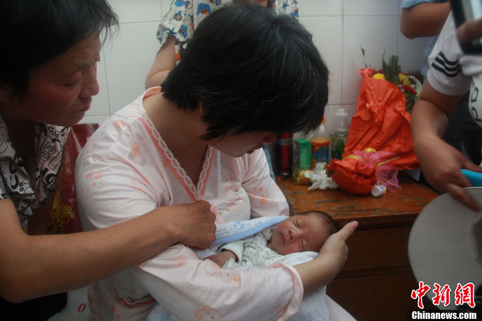 圖為久別重逢，獲救嬰兒母親悉心撫摸愛子。張一辰 攝