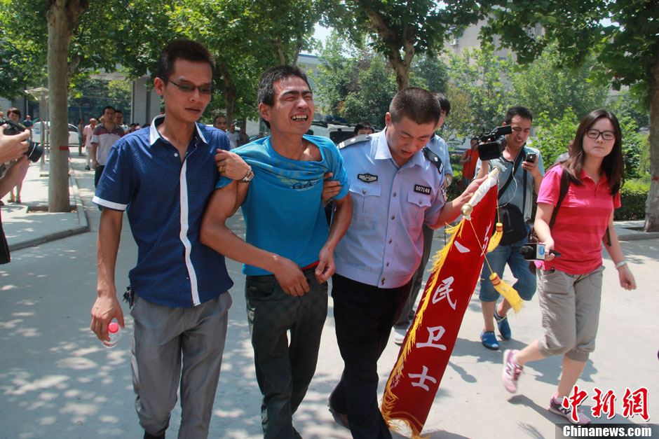 圖為獲救嬰兒父親情緒一度失控，當(dāng)?shù)鼐焦ぷ魅藛T對(duì)其進(jìn)行攙扶。張一辰 攝