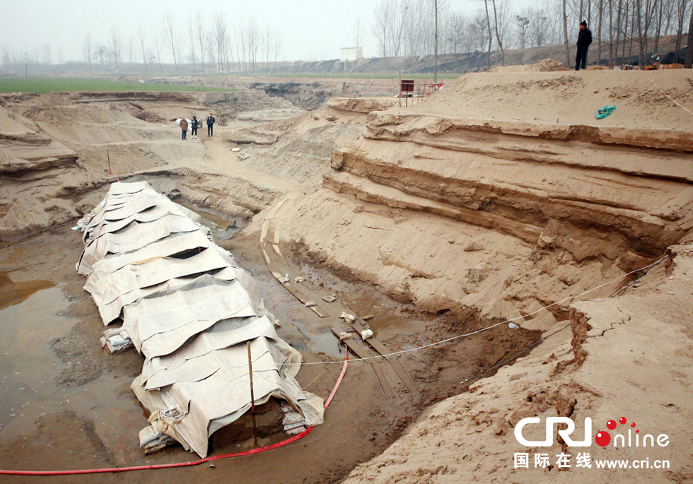 2014年1月6日，河南洛陽古沉船發(fā)掘現(xiàn)場，近日有雨雪天，考古人員給古沉船披上一層“雨衣”。