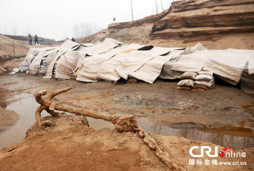 2014年1月6日，河南洛陽古沉船發(fā)掘現(xiàn)場，古沉船鐵錨從見天日，靜靜地躺在古船旁。