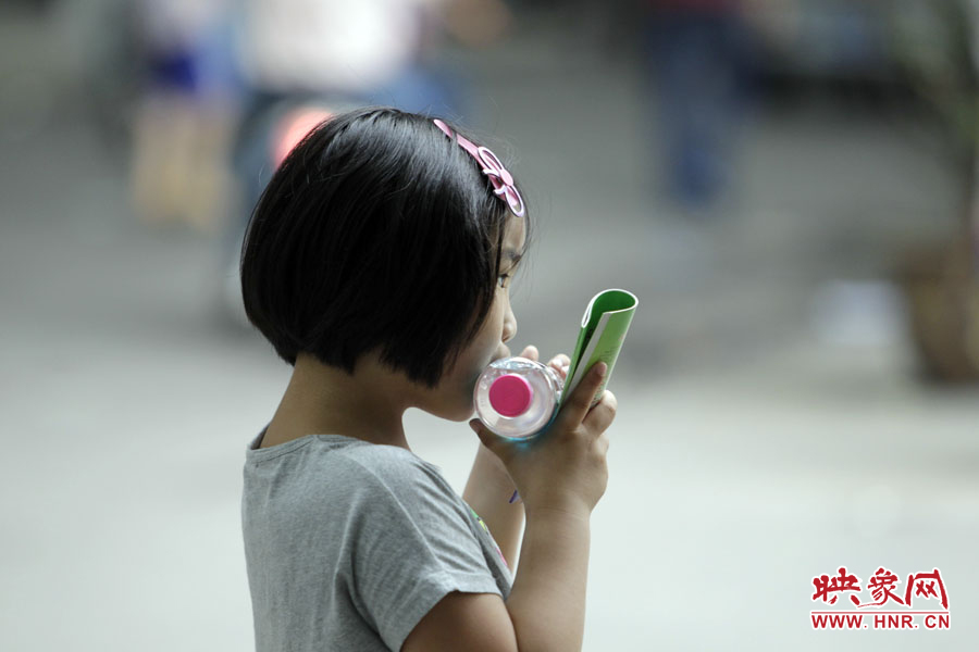 6月7日，鄭州回中考點，一名孩子拿著一瓶礦泉水，等待哥哥走出考場