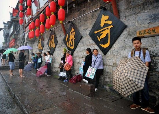 　4月29日上午11時20分，一些游客和古城當?shù)氐木用穸阍谝粋€酒吧的屋檐下避雨。這些當?shù)鼐用褚詾橛慰团恼罩\生，一場降雨讓他們的生意更加清淡。