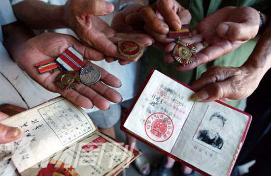 幾位志愿軍老兵展示自己的立功證、傷殘軍人證與勛章