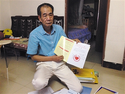 翻出一家網(wǎng)站贈(zèng)予的“中國好人”證書，區(qū)少坤單膝跪在地上，“你看，我是中國好人啊?！?范春旭 攝