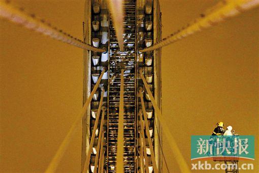 截至今日零時(shí)，男子仍未有下橋舉動(dòng)。圖為公安和消防人員乘消防云梯在高空上和男子交談。