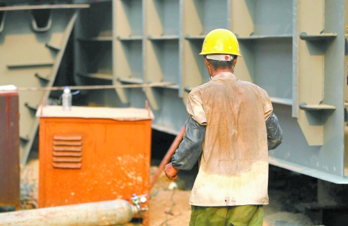 工地上，一建筑工人的衣服被汗水浸透。