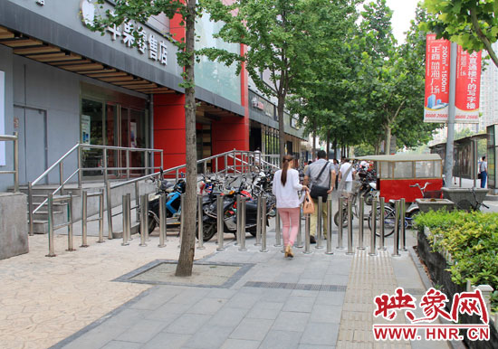 圖中道路左側的無障礙通道被鋼管隔離,右側的盲道也被侵占。