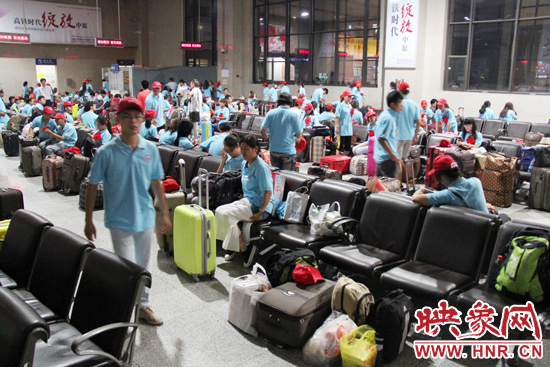 大學(xué)生志愿者在火車站候車室內(nèi)整裝待發(fā)。