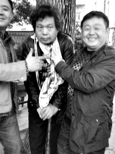 兩名接訪人員與患有癌癥的訪民段新德合影時，面帶笑容擺出勝利的手勢。