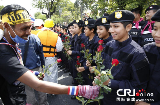 2013年12月03日,曼谷總理府與曼谷警署允許反政府示威民眾進(jìn)入,雙方進(jìn)入暫時(shí)“停戰(zhàn)”狀態(tài)迎接泰王生日。曼谷警察總署,女警們手持鮮花送給反政府示威民眾。圖片來(lái)源:Manish Swarup/東方IC