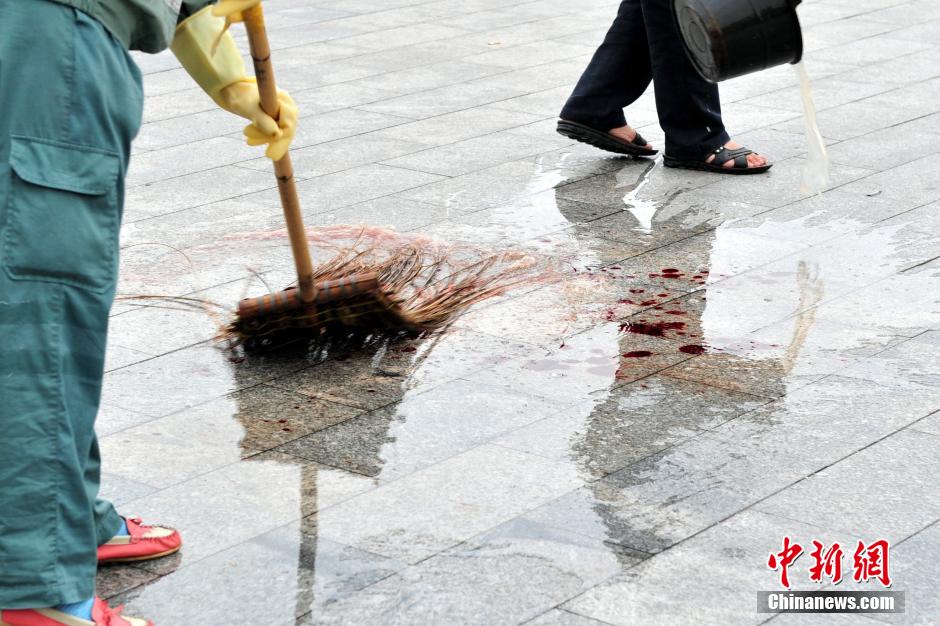 圖為環(huán)衛(wèi)工人在清理案發(fā)地點(diǎn)的血跡。