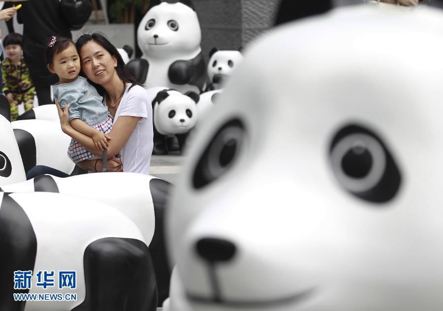 6月2日，一位家長(zhǎng)帶著孩子在上海街頭和大熊貓模型合影。