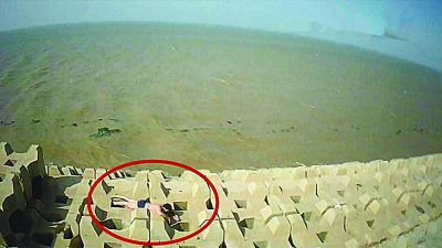 孫正龍游上岸，趴在海邊精疲力盡。