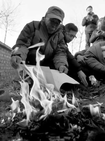 李三仁在兒子墳前焚燒再審無罪判決文書的復(fù)印件。新華社發(fā)