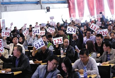 競(jìng)拍者正在練習(xí)舉牌動(dòng)作，以便拍賣(mài)時(shí)讓工作人員看清號(hào)牌。