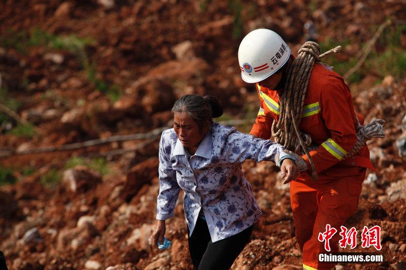 一位消防戰(zhàn)士將一位失去親人的老人扶離滑坡點。