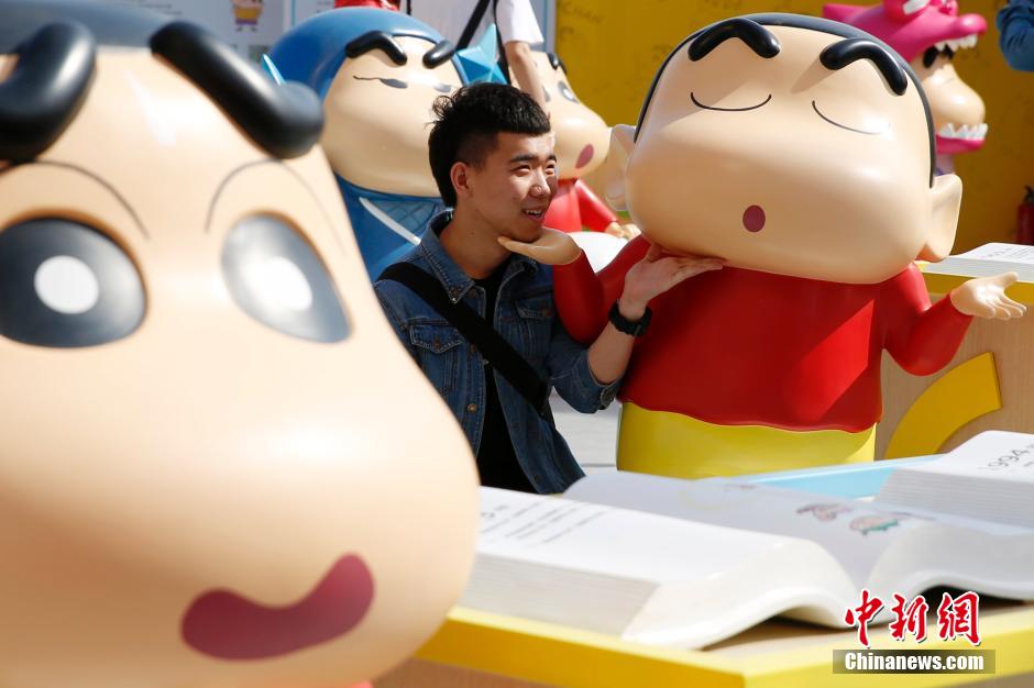 4月22日，游客與蠟筆小新合影。“蠟筆小新25周年紀(jì)念特展”日前在北京開展，吸引了不少市民游客。