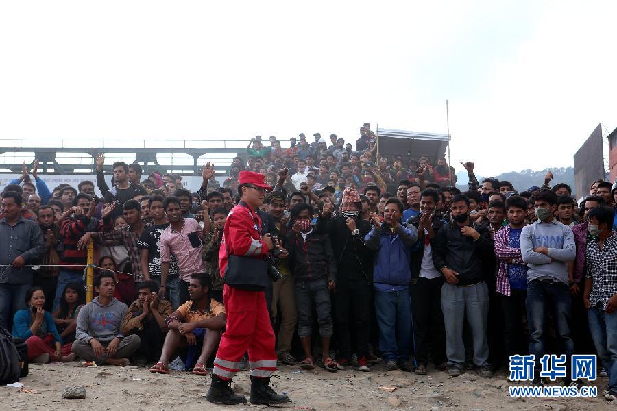圍觀的尼泊爾民眾在中國(guó)國(guó)際救援隊(duì)成功搜救出幸存者后向搜救隊(duì)員歡呼致意。