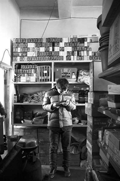 1月21日，周瑋在自家的超市里玩計(jì)算器。