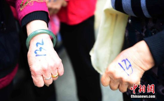 圖為10月28日，在江西九江市一家羊絨皮草服裝服飾博覽會現(xiàn)場，老人們正在頂著寒風排隊等待領取10元代金劵。